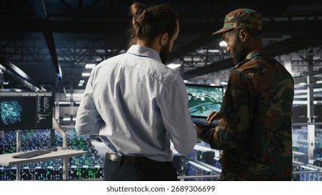 Army operators in data center using laptop to run drone control software, looking at mission map overlay. Military experts doing strategic deployment of autonomous aerial vehicles