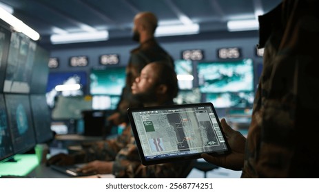 Army professional employing AI tech to improve military combat systems and missiles monitoring. African american IT admin uses neural networks to enhance combat operational capabilities, camera B