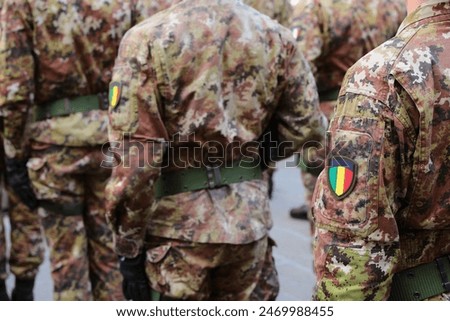 army soldier marching in parade wearing camouflage uniform and crest flag with green yellow and red colors