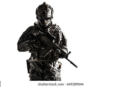 Army soldier in Protective Combat Uniform holding Special Operations Forces Combat Assault Rifle. Studio shot, dark contrast, cropped, desaturated, isolated on white background