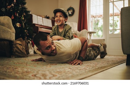 Army soldier spending quality time with his son at Christmas. Happy military dad spending the holidays with his son after deployment. Father and son having a joyful reunion at home. - Powered by Shutterstock