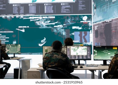 Army staff examining surveillance footage on big screen in operation room, gathering intelligence for a new defense mission. Diverse group of troopers working on reconnaissance activity. - Powered by Shutterstock