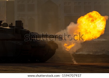 Army tanks close up shooting and driving in the desert town in war and military conflict. Military concept of war and explosions.