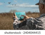 Army technologies. Warfare analytic operator checking coordination of the military team with drones. Military commander with a digital tablet device with augmented reality operating troops outdoors.