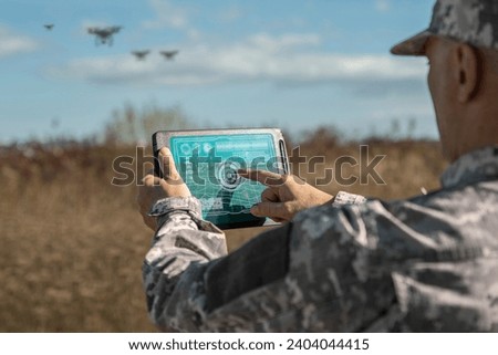 Army technologies. Warfare analytic operator checking coordination of the military team with drones. Military commander with a digital tablet device with augmented reality operating troops outdoors.