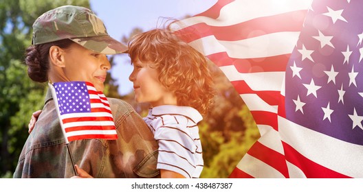 Army woman carrying son against focus on usa flag - Powered by Shutterstock