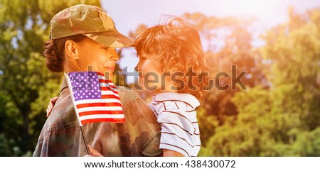 Army woman carrying son while looking at each other