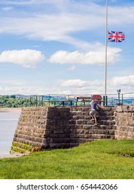 Arnside, Lancashire, UK. May 23rd 2017. Dog Walker Taking A Dangerous Shortcut By Climbing The Wall Of The Pier At Arnside, Lancashire, UK