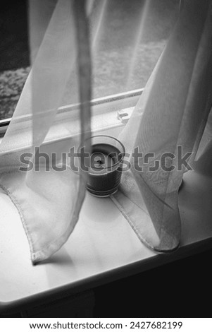 Aroma candle near curtains and a window black and white