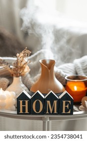 Aroma composition with a modern aroma oil diffuser, candles and a knitted element.
