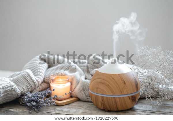 Aroma\
composition with a modern aroma oil diffuser on a wooden surface\
with a knitted element, candle and\
lavender.