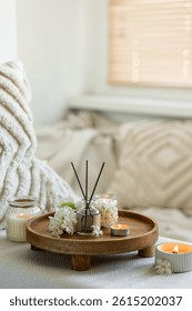 Aroma diffuser, burning candle, blooming hyacinth flowers and perfume on wooden bamboo tray. Cozy home decor, hygge and aromatherapy concept. Comfortable atmosphere, spring delicious fresh smell