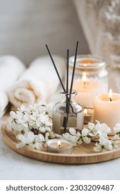 Aroma diffuser, burning candle, cherry blooming flowers and perfume on wooden bamboo tray. Cozy home decor, hygge and aromatherapy concept. Comfortable atmosphere, spring delicious fresh smell - Shutterstock ID 2303209487