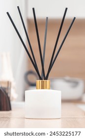 Aroma diffuser for perfumed liquid and reed sticks in the room on a wooden table.