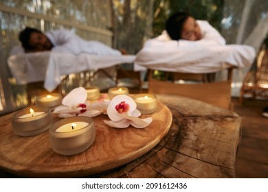 Aroma massage for couple at spa resort. Couple lying on massage tables during day-spa and romantic weekend with candles and orchid flowers
