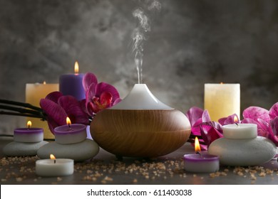 Aroma oil diffuser, candles and flowers on table - Shutterstock ID 611403038
