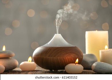 Aroma oil diffuser and candles on blurred background