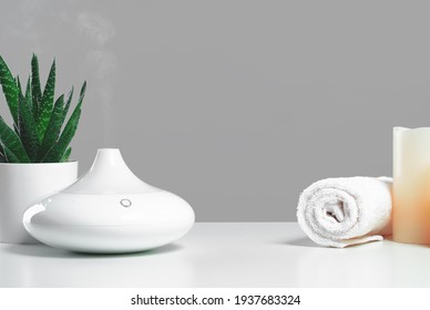 Aroma oil diffuser and candles with white towel on table. Spa, relaxation aromatherapy or yoga studio concept. Copy space