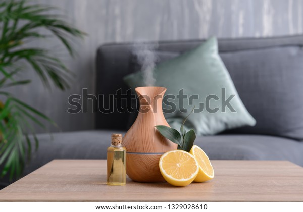 Aroma oil\
diffuser and citrus fruit on table in\
room
