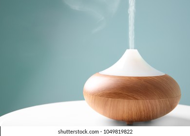 Aroma oil diffuser on table against color background