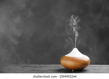 Aroma oil diffuser on table against grey background. Air freshener