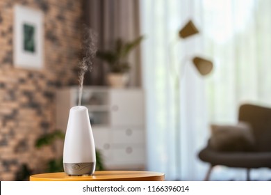Aroma oil diffuser on table against blurred background. Air freshener