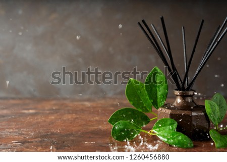 Aroma reed diffuser bottle home fragrance with rattan sticks and falling water drops, splashes on the surface with scents of freshness rain with copy space