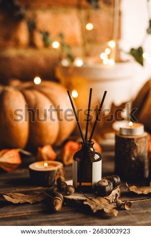 Aroma reed diffuser, pumpkins, knitted warm sweaters, candles, dry leaves on wooden table. Concept of house decor, apartment seasonal fragrance. Thanksgiving. Autumn mood, cozy fall home atmosphere