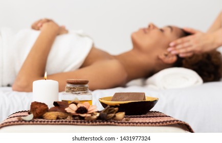 Aroma Spa. Afro Woman Enjoying Facial Massage In Luxury Spa With Candle On Foreground