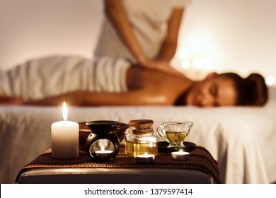 Aroma Spa. Woman Enjoying Massage In Luxury Spa With Candle On Foreground