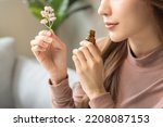 Aromatherapy, asian young woman, girl hand holding flower, bottle of essential perfume oil, enjoying smell fragrance of herbal from medicine natural organic at home.Therapy treatment, beauty skin care
