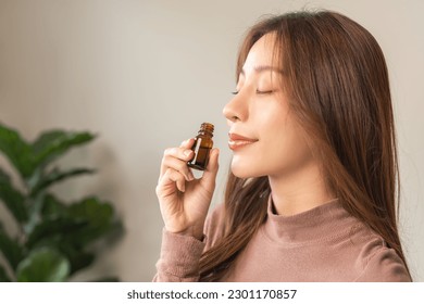 Aromatherapy, attractive asian young woman, girl face expression enjoying smell fragrance of herbal from medicine natural organic essential perfume oil at home. Therapy treatment, beauty skin care. - Shutterstock ID 2301170857