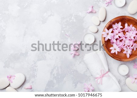 Aromatherapy, beauty, spa background with massage pebble, perfumed flowers water and candles on stone table top view. Relaxation and zen like concept. Flat lay.