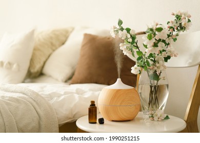 Aromatherapy Concept. Aroma oil diffuser on chair against in the bedroom. Air freshener. Ultrasonic aroma diffuser for home - Shutterstock ID 1990251215