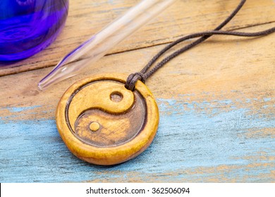 aromatherapy concept - essential oil diffuser ceramic pendant with yin and yang symbol, eye dropper and blue bottle