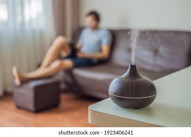 Aromatherapy Concept. Wooden Electric Ultrasonic Essential Oil Aroma Diffuser and Humidifier. Ultrasonic aroma diffuser for home. Man resting at home - Shutterstock ID 1923406241