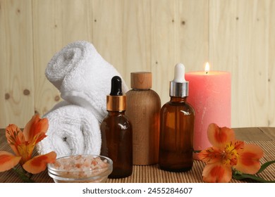 Aromatherapy. Essential oil in bottles, candle, sea salt, flowers and towel on bamboo mat, closeup - Powered by Shutterstock