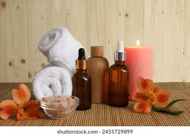 Aromatherapy. Essential oil in bottles, candle, sea salt, flowers and towel on bamboo mat - Powered by Shutterstock