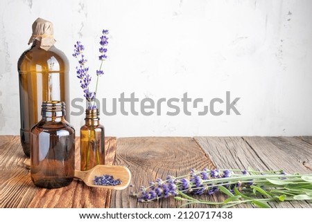Aromatherapy and essential oil, herbal natural cosmetics, alternative medicine and naturopathy concept. Bunch of lavender flowers and glass bottles on wooden background
