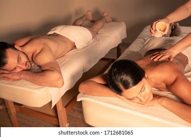 aromatherapy, hot oil massage. Couple enjoying relaxing massage with aroma oil and burning candle. Mixed couple getting aromatherapy