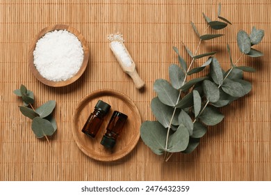 Aromatherapy products. Bottles of essential oil, sea salt and eucalyptus branches on bamboo mat, flat lay - Powered by Shutterstock