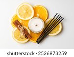 Aromatic arrangement featuring citrus slices and a scented candle on a white surface