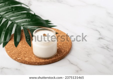 aromatic Candle on a cork stand in the bathroom with green leaf, relaxation and body care, spa