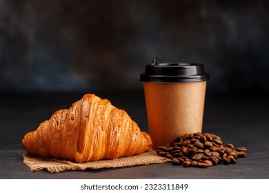 Aromatic coffee in a paper cup paired with a flaky croissant. With copy space - Powered by Shutterstock