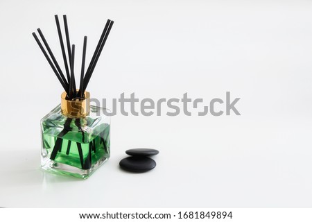 
An aromatic diffuser for the home that promotes relaxation. Bottle with liquid of natural natural color and wooden sticks on a white background. Copy space for text.