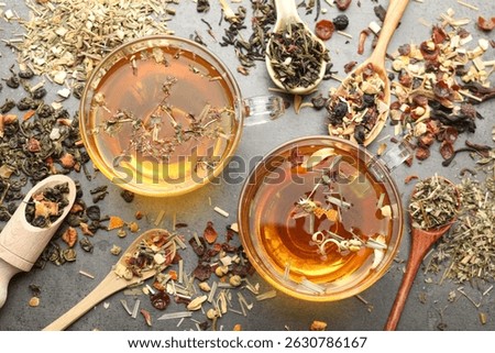 Aromatic herbal tea and dry leaves on grey table, flat lay