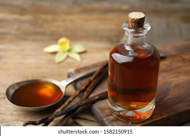 Aromatic homemade vanilla extract on wooden table, closeup. Space for text