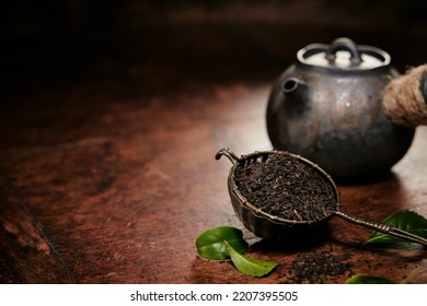 Aromatic Loose Tea Fro Brewing In Metal Ladle Placed On Table With Leaves And Old Fashioned Metal Teapot In Kitchen