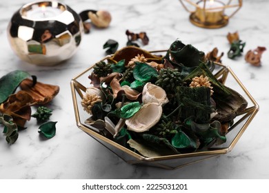 Aromatic potpourri of dried flowers in bowl on white marble table, closeup