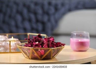 Aromatic potpourri of dried flowers in decorative bowl and burning candles on table indoors, space for text